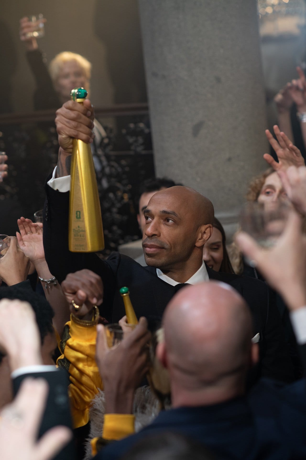 Bottle in hand, he moves through the crowd, pauses to kiss it in homage to his iconic 1998 FIFA World Cup victory with France, and then raises it triumphantly, a moment that sends the celebration soaring.